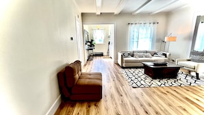 Un salon spacieux avec un canapé marron, une table basse et un tapis à motifs.