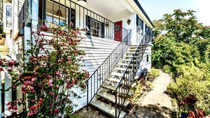 Une maison à deux étages avec un porche, un escalier et un jardin.