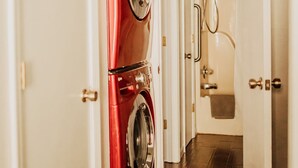 A laundry room with a red washer and dryer, a shower, and a wooden floor. - Serene on 17 Pointe Royale Walk-In Condo, Water Views (Branson)