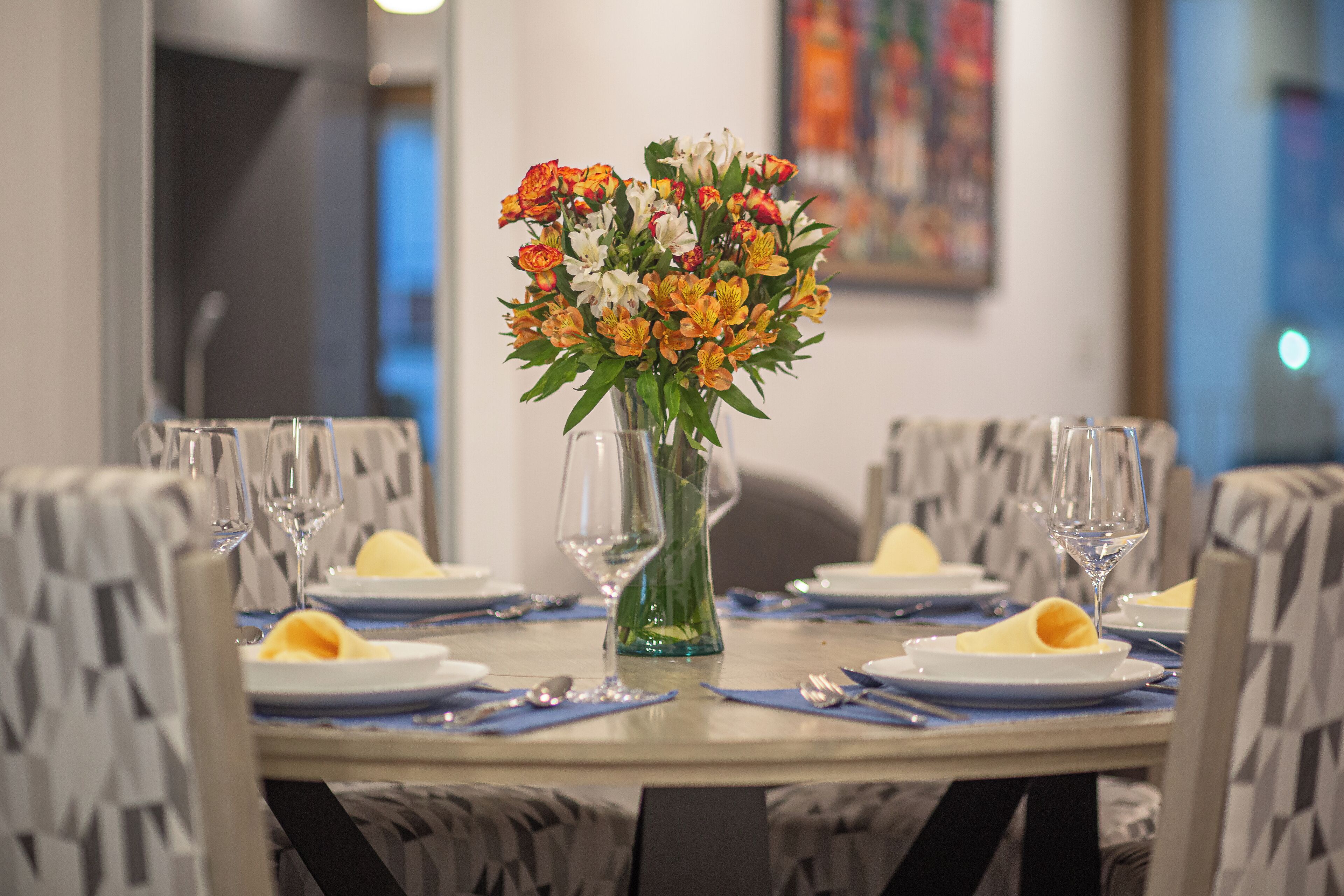 A dining table set with plates, cutlery, and a vase of flowers.
