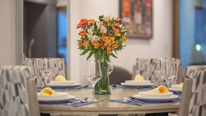 A dining table set with plates, cutlery, and a vase of flowers. - La Palapa beachfront fully renovated condo!  In the heart of the Romantic Zone. (Puerto Vallarta)