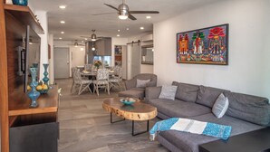 A modern living room with a gray sofa, a wooden coffee table, and a dining area in the background. - La Palapa beachfront fully renovated condo!  In the heart of the Romantic Zone. (Puerto Vallarta)