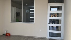 A room with a large window, a door with multiple glass panels, and a water heater on the floor. - La cuna del buen vestir (Colonia la Cruz)