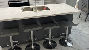 A modern kitchen with a large island, stainless steel sink, and bar stools. - La cuna del buen vestir (Colonia la Cruz)