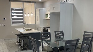 A modern kitchen with a central island, a dining area with six chairs, and a large window with pendant lighting. - La cuna del buen vestir (Colonia la Cruz)