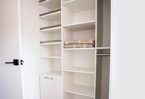 Un armario blanco con varios estantes y una puerta con picaporte.