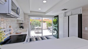 A modern kitchen with a built-in oven, a refrigerator, and a dining area with a view of a garden. - Desert Retreat Relax, Recharge, Views, Resort Living, Office + Monthly Discount (Palm Springs)