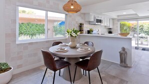 A modern dining area with a round table, chairs, a vase with flowers, and a view of the outdoors. - Desert Retreat Relax, Recharge, Views, Resort Living, Office + Monthly Discount (Palm Springs)