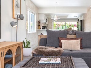 Een moderne woonkamer met een bank, een bijzettafeltje met een tijdschrift, een lamp en een potplant.