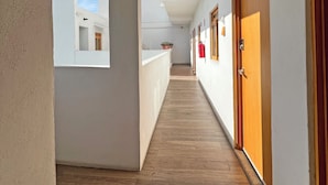 A corridor with wooden flooring, white walls, and wooden doors. - Casa Palo Verde, Standard bedroom 1 queen bed, Full Kitchen (Cabo San Lucas)