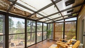 A sunroom with large windows, wooden chairs, a small table, and a potted plant. - 1Br Hidden Gem overlooking Wetland Dog Friendly (Flagstaff)