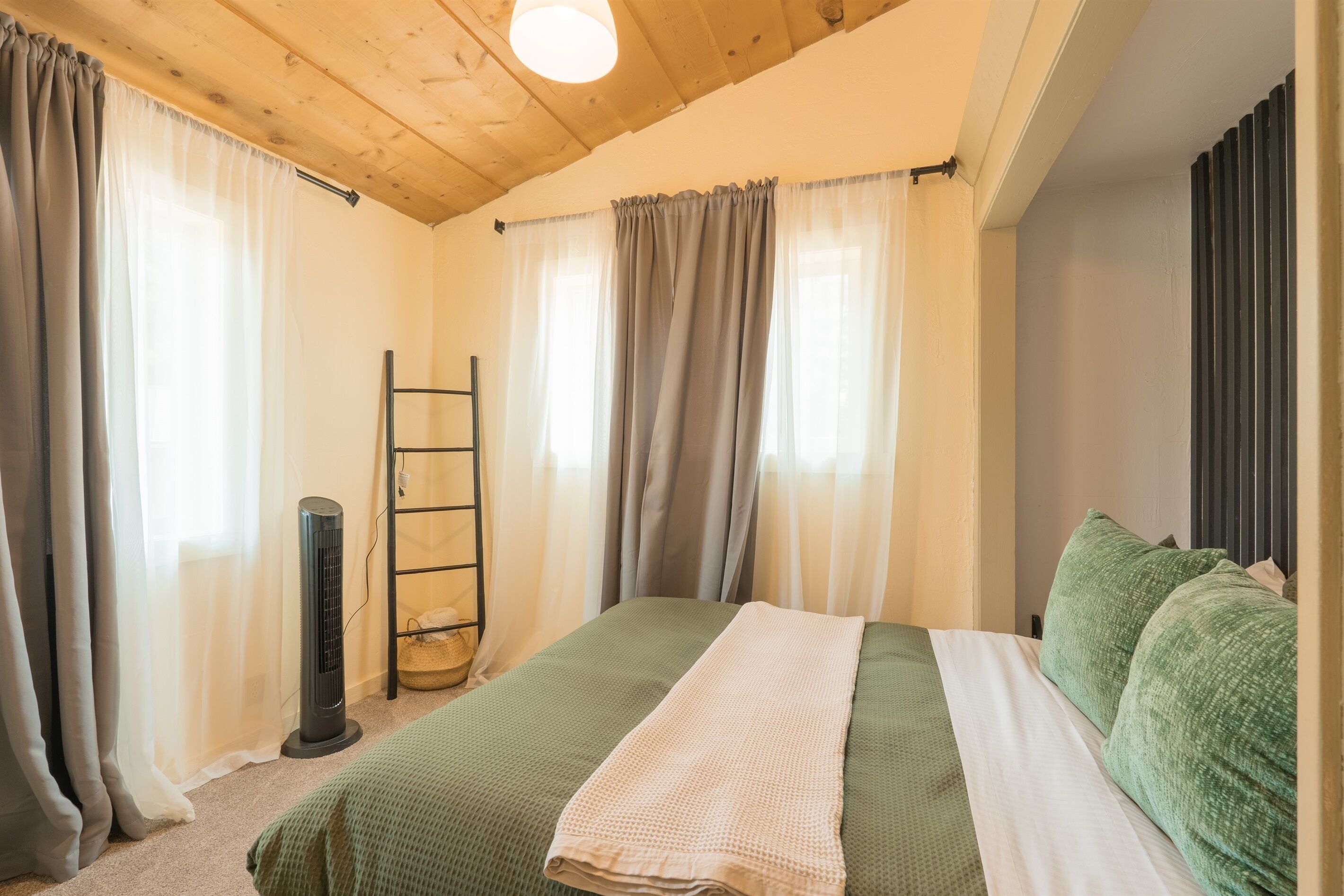 Een slaapkamer met een bed, een elektrische kachel en gordijnen.