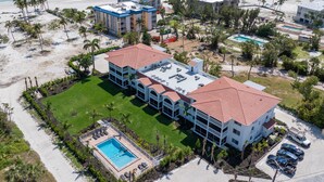 A resort with a pool, multiple buildings, and a beach view.