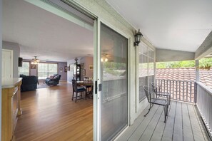 Un ampio soggiorno con pavimento in legno, un'area pranzo con tavolo e sedie, e un balcone con ringhiera e vista esterna.