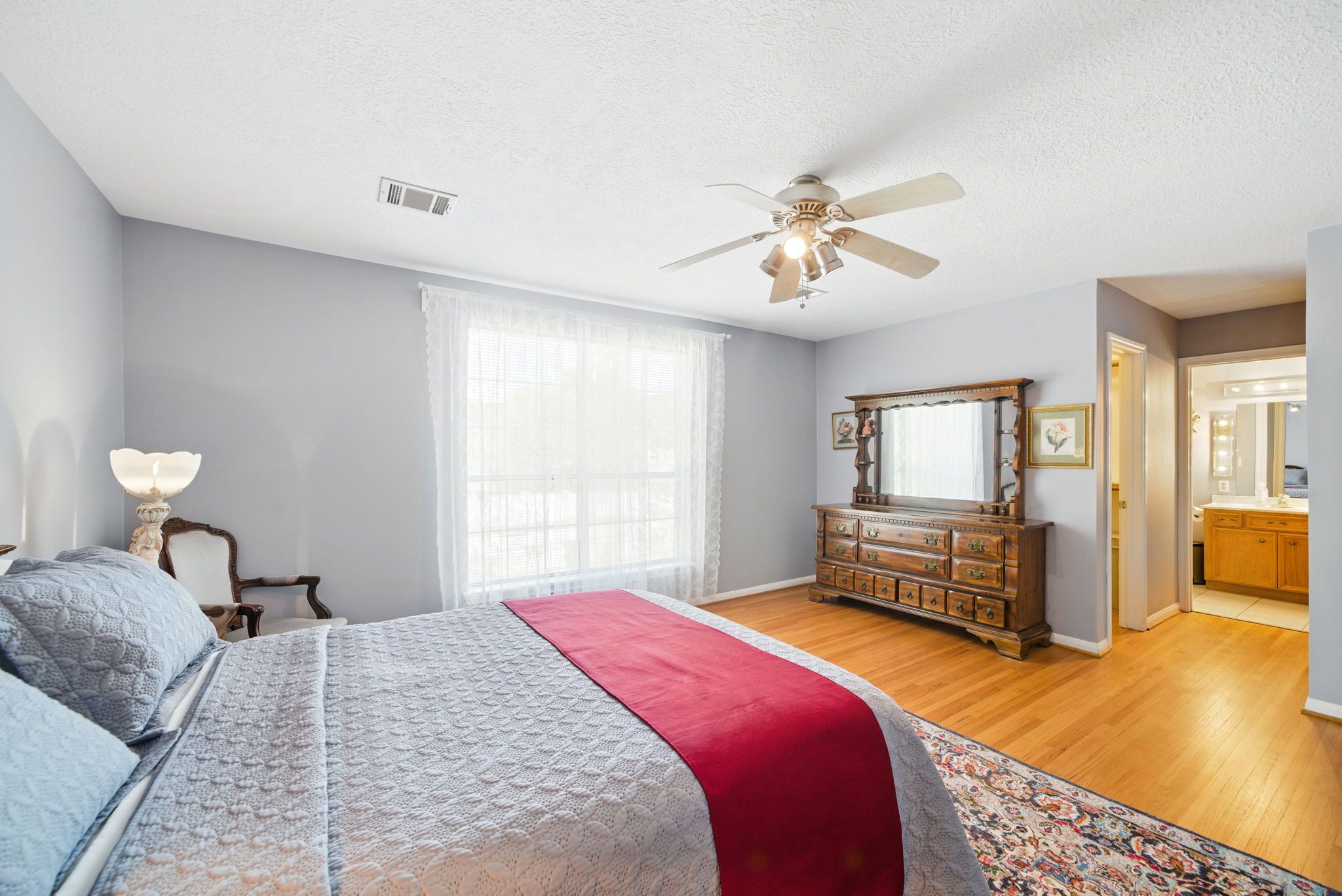 A bedroom with a bed, dresser, and a ceiling fan.