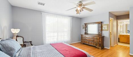 A bedroom with a bed, dresser, and a ceiling fan.