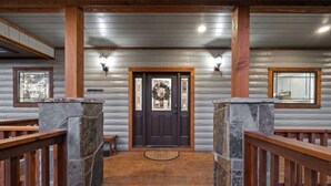 A wooden cabin entrance with a stone pillar, a wooden door, and a small window. - 3 Masters, w/Bunk Room, Shuffle Board, Arcades, Hot Tub-Great For Families (Broken Bow)