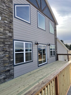 A two-story house with a stone facade, large windows, and a wooden deck. - 7 bedroom home with great views of Glendo Reservoir and Laramie Peak. (Glendo)