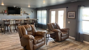 A living room with leather recliners, a wooden dining table, and a TV mounted on the wall.
