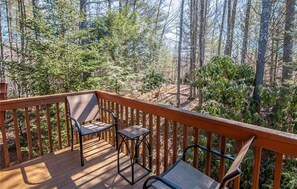 Enjoy a serene forest view from this deck with two comfortable chairs and a small table.