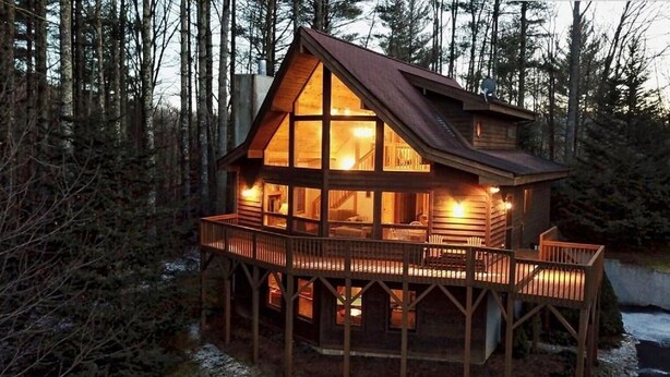 Eine Holzhütte mit einem Balkon, umgeben von Bäumen.
