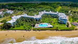 Ein Resort mit mehreren Gebäuden, einem zentral gelegenen Pool und einem Strand.