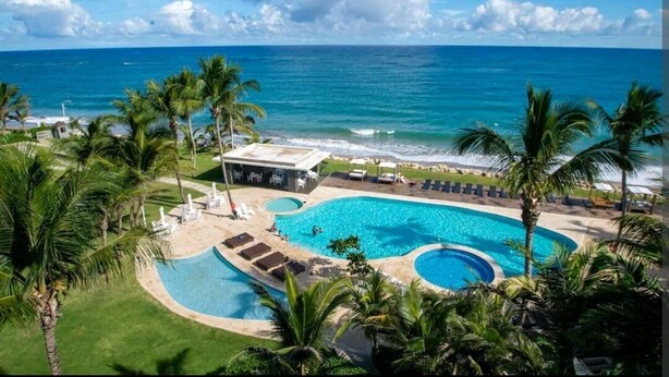 Ein Resort mit großem Pool, Palmen und Blick auf den Ozean.