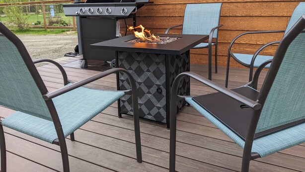 En terrasse med grill og et bord med stole.