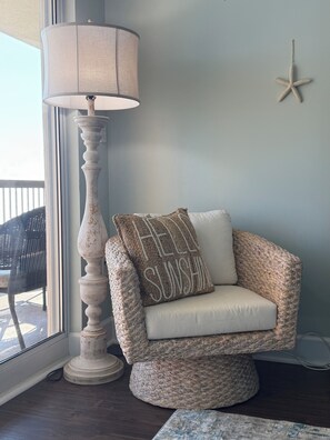Un rincón de una habitación con un sillón tejido, una lámpara y una decoración con forma de estrella de mar en la pared.