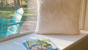 A window seat with a magazine, a fluffy pillow, and a blue Adirondack chair. - Cozy Canterbury | Dog-friendly oasis in Bend (Bend)