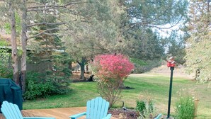 A wooden deck with a table and four Adirondack chairs. - Cozy Canterbury | Dog-friendly oasis in Bend (Bend)