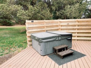 Ein Whirlpool mit einer Holzterrasse und einem Holzzaun im Hintergrund.