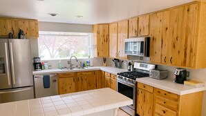 A modern kitchen with wooden cabinets, stainless steel appliances, and a large window. - Cozy Canterbury | Dog-friendly oasis in Bend (Bend)