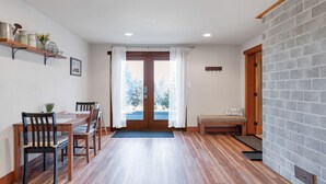 Un comedor con una mesa y sillas de madera, un banco y vistas a través de una puerta.