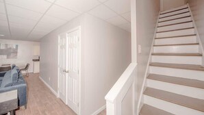 Un escalier menant à l’étage supérieur, une porte, un canapé et une petite table dans un couloir.