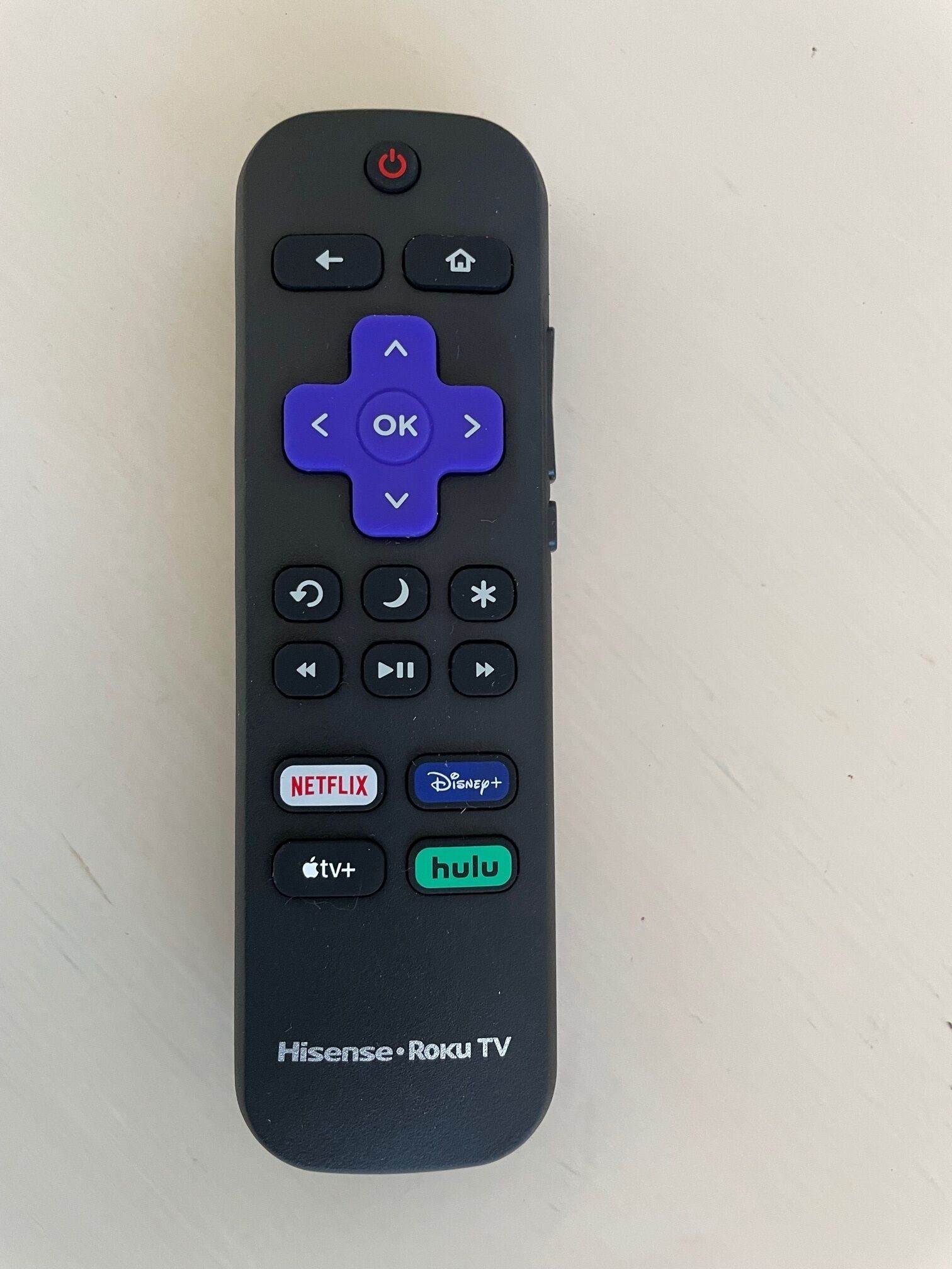 A remote control with directional pad, navigation buttons, and app icons for Netflix, Disney+, Apple TV+, Hulu, and Roku TV.