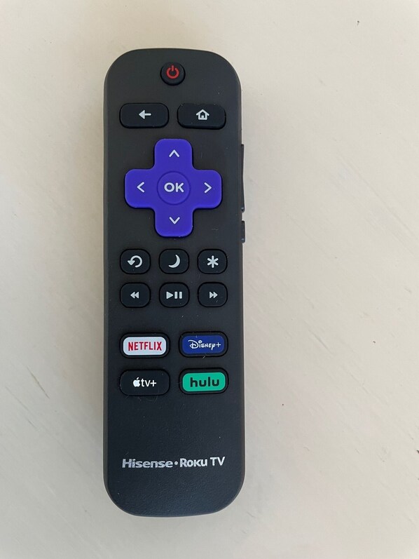 A remote control with directional pad, navigation buttons, and app icons for Netflix, Disney+, Apple TV+, Hulu, and Roku TV.