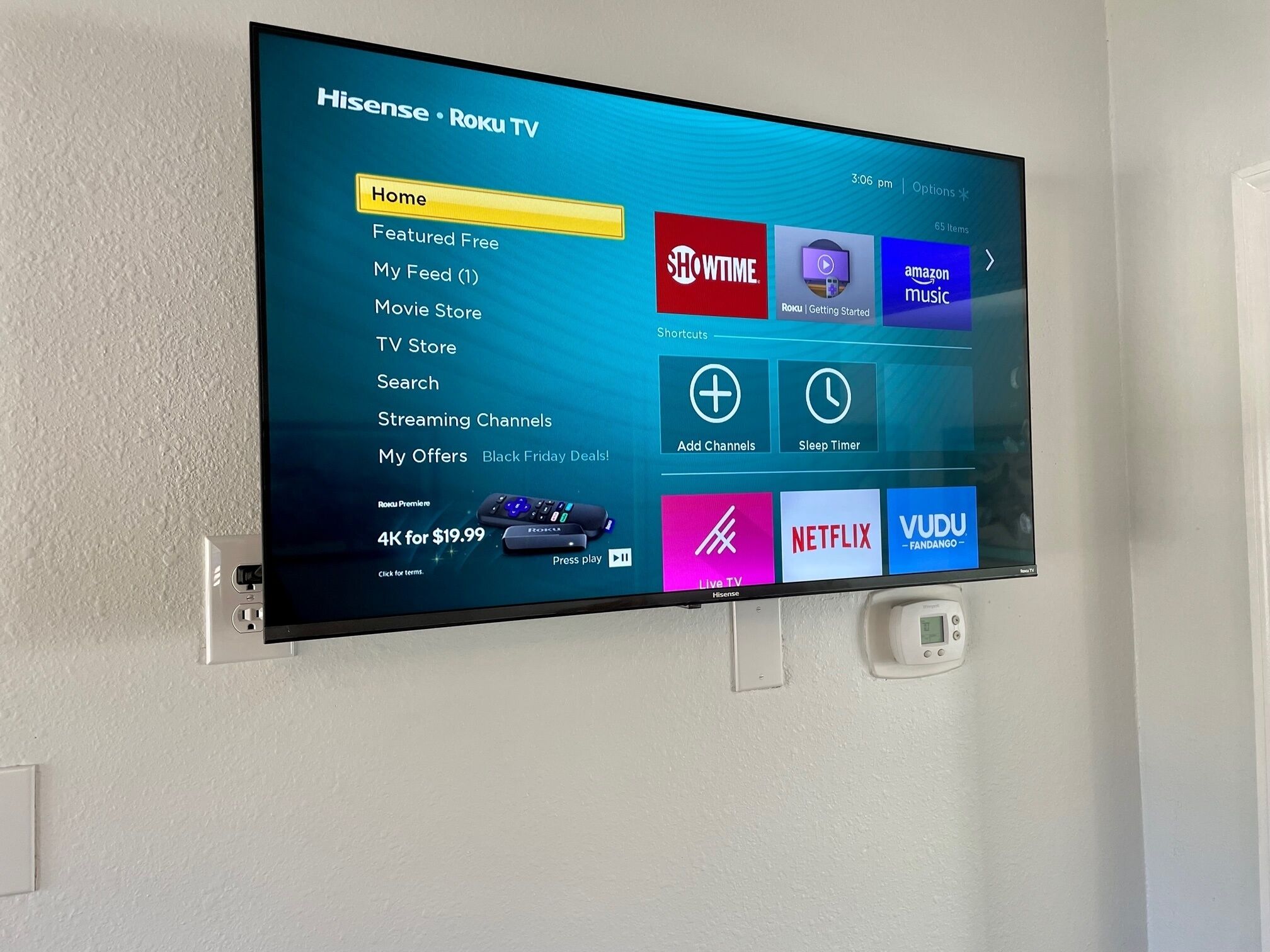Televisor de pantalla plana montado en la pared, mostrando la interfaz Roku TV con varios íconos y opciones de servicios de streaming.