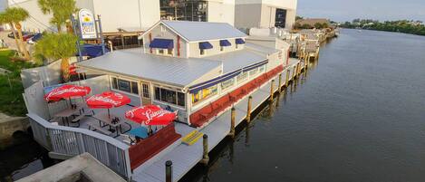 A riverfront restaurant with outdoor seating and a view of the water.