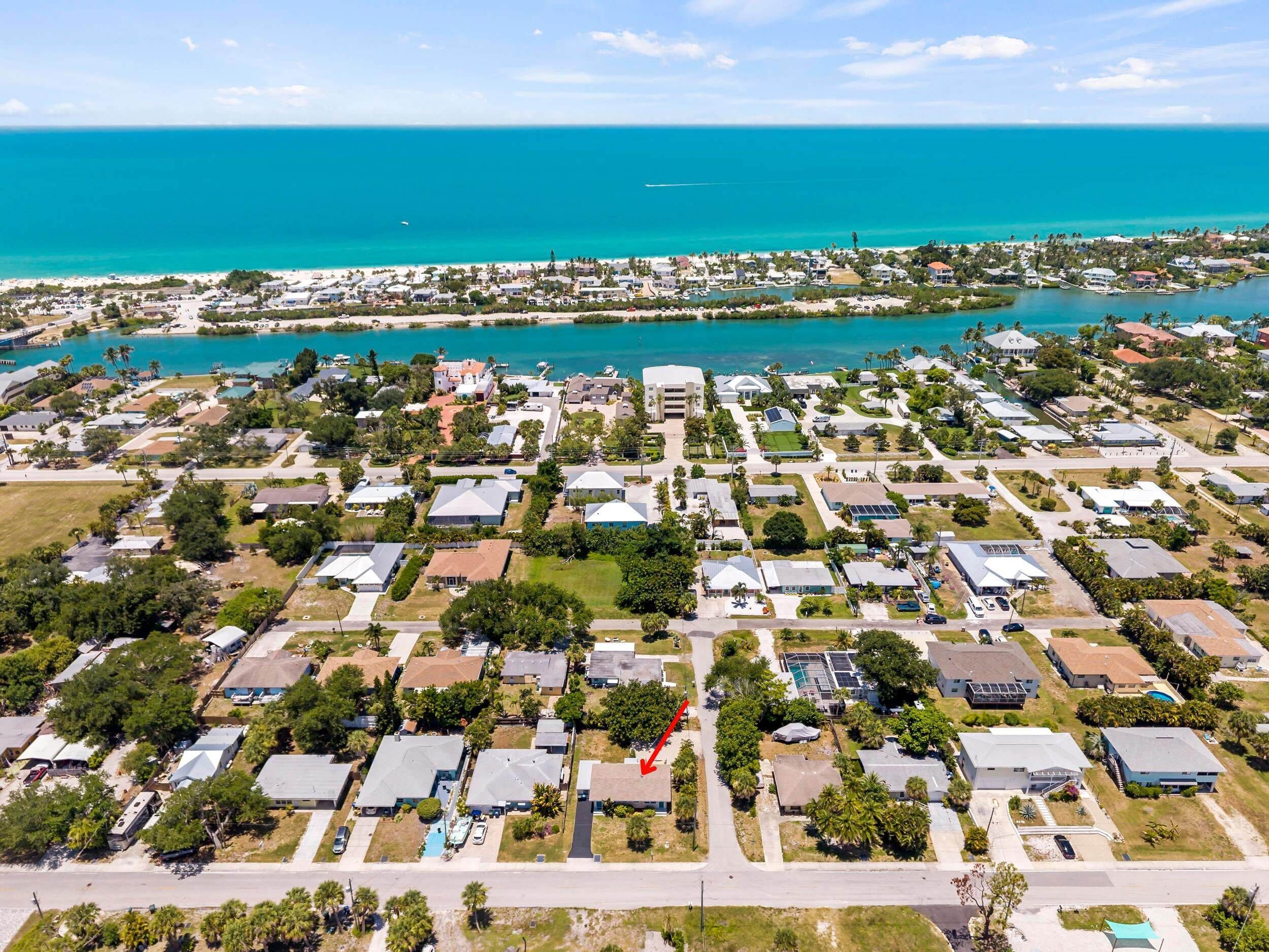 Vista aérea de una zona residencial costera con casas, calles y un puerto deportivo.