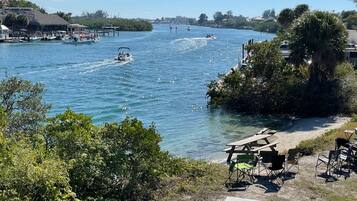 Une vue sur le fleuve, avec des bateaux, un quai et un espace pique-nique équipé de chaises et de tables.