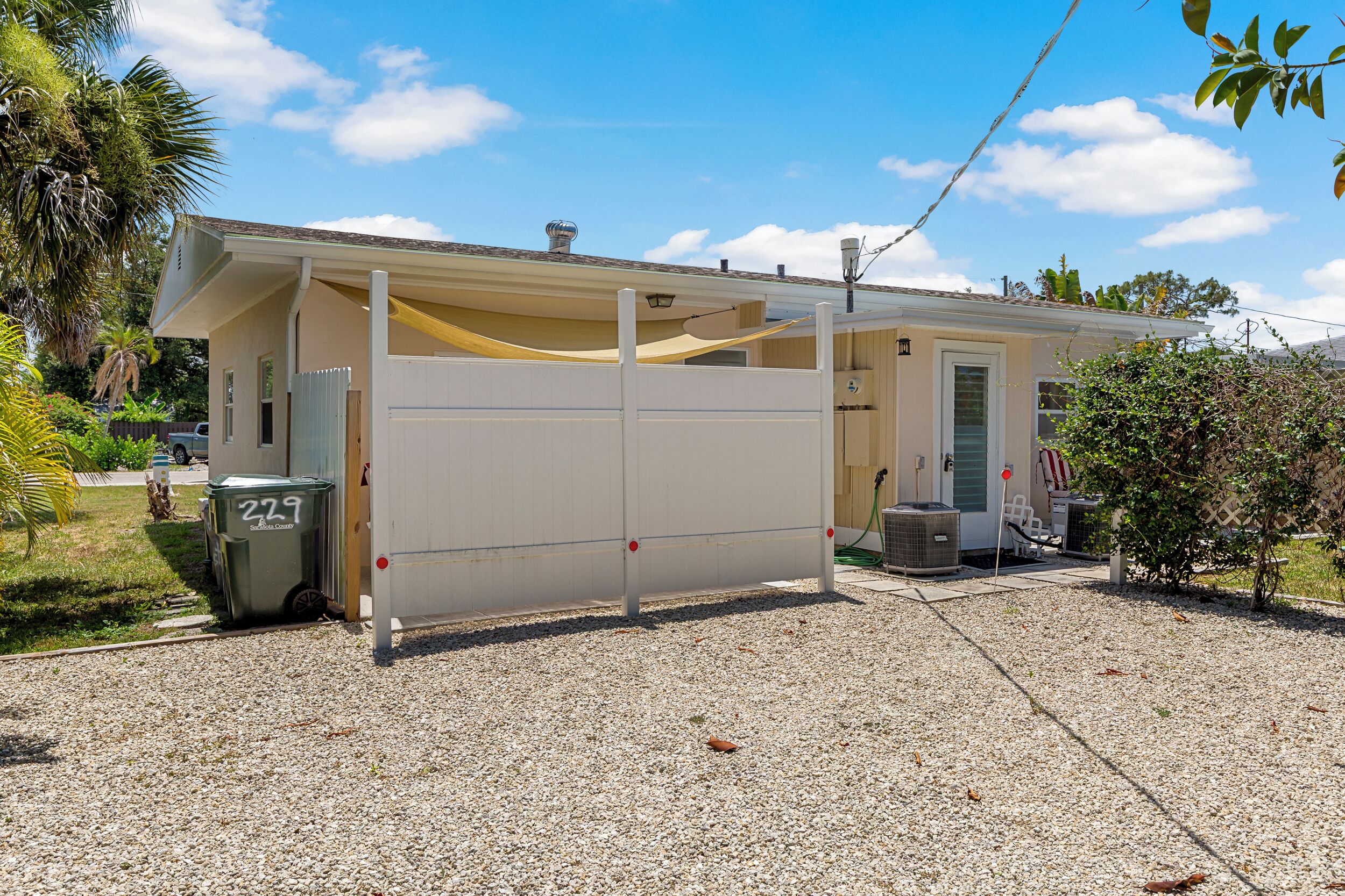 Une maison de plain-pied dotée d’un porche couvert, d’un petit garage attenant et d’une allée en gravier.