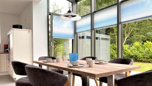 A modern dining area with a wooden table, six dark chairs, and a hanging light fixture.