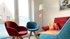 A modern living room with a red sofa, a blue armchair, and a wooden coffee table.