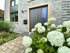 A modern building with a brick facade, a large door, and a mailbox. - Welcome to Haus Friesland 10! - House "Friesland 10", Am Alten Deich (Varel)