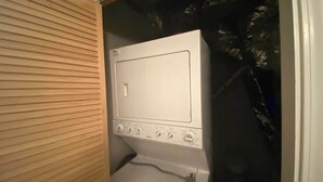 Eine weiße Waschmaschine in einem Waschraum mit einer Wand aus Holzpaneelen.