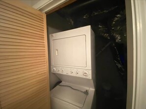Una lavatrice bianca in una lavanderia con una parete rivestita in legno.