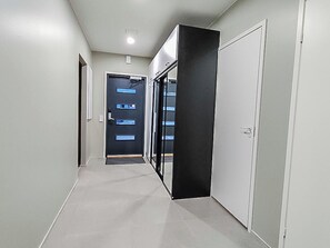 Un couloir avec une porte, un panneau noir et une porte blanche.