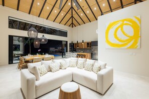 Ein modernes Wohnzimmer mit Ecksofa, Esstisch und Pendelleuchten.