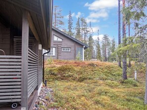 En hytte med træfacade, veranda og udsigt til en skovklædt skråning.